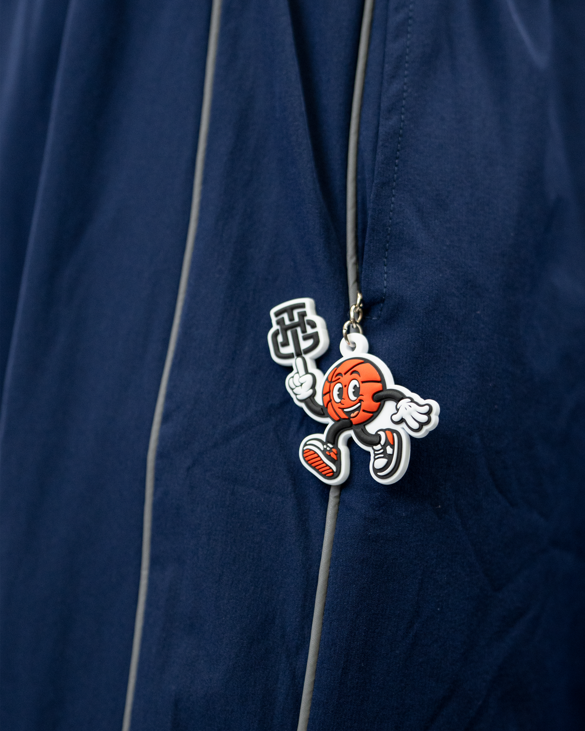 THG Mascot Keychain close up on a Navy Blue Cropped Trackpants zipper