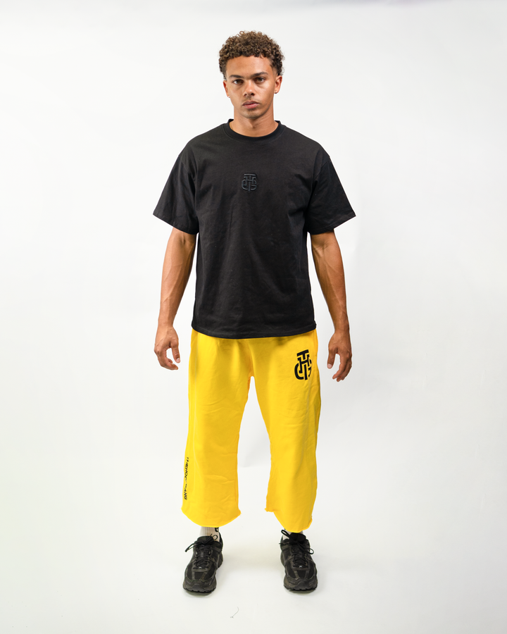 Model wearing THG Yellow Cropped Sweatpants with a black tee, front view
